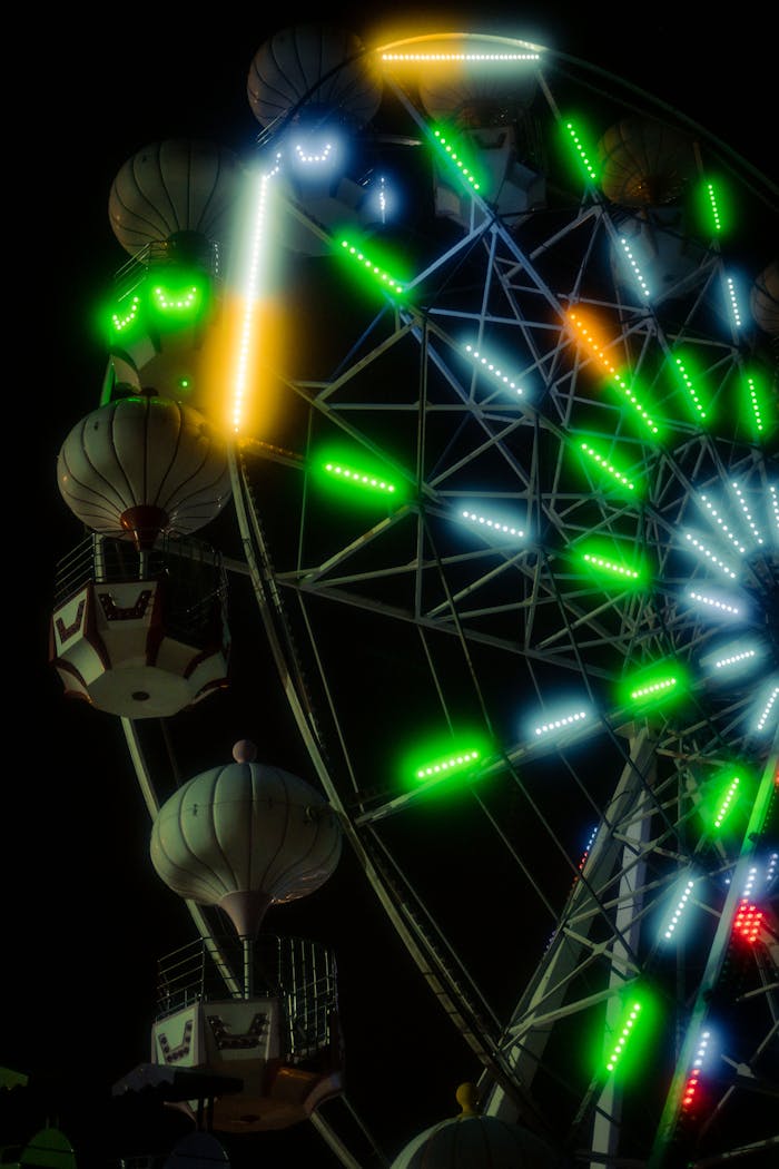 A colorful Ferris wheel shines brightly against the night sky at a lively carnival.